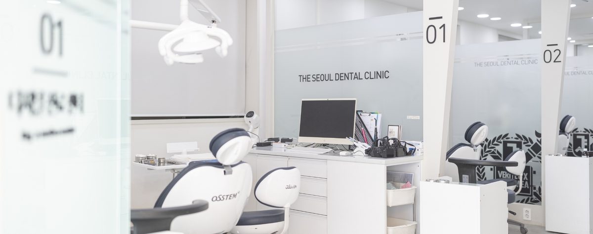 Two treatment bays at The Seoul Dental, numbered 01 and 02, separated by frosted glass partitions marked The Seoul Dental Clinic