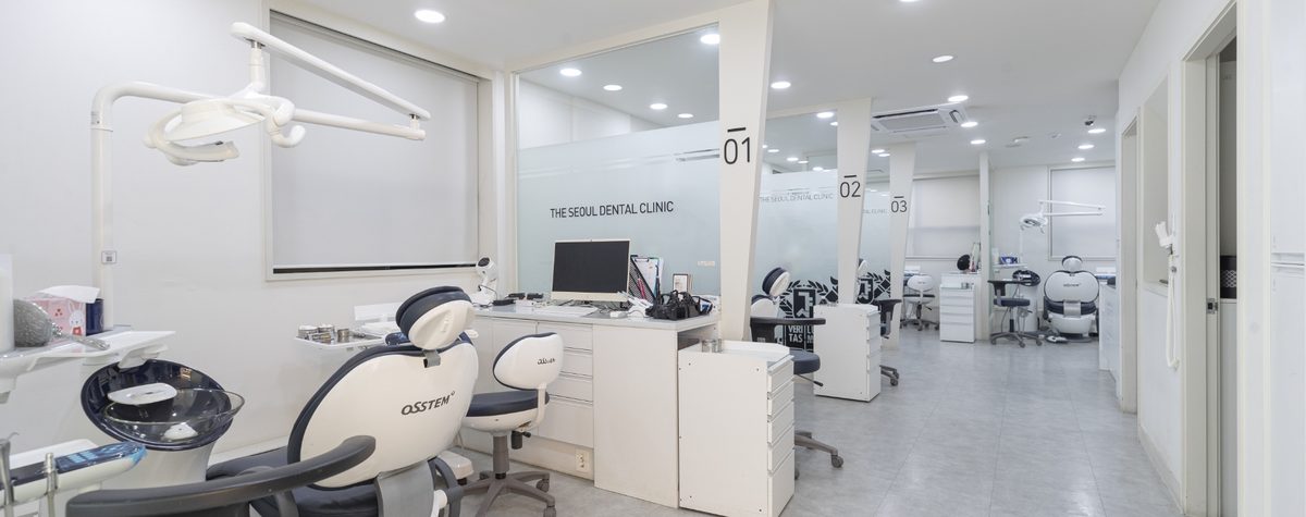 The treatment area at The Seoul Dental in Seongnam, with a dental chair under an overhead light and further numbered bays along the corridor behind
